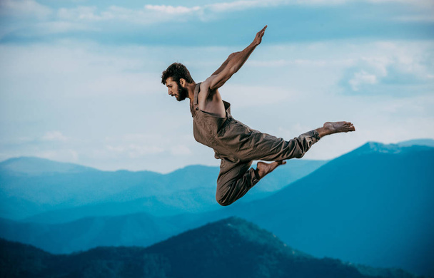 Красивий активний молодий чоловік танцює під час стрибків у повітрі
 - Фото, зображення