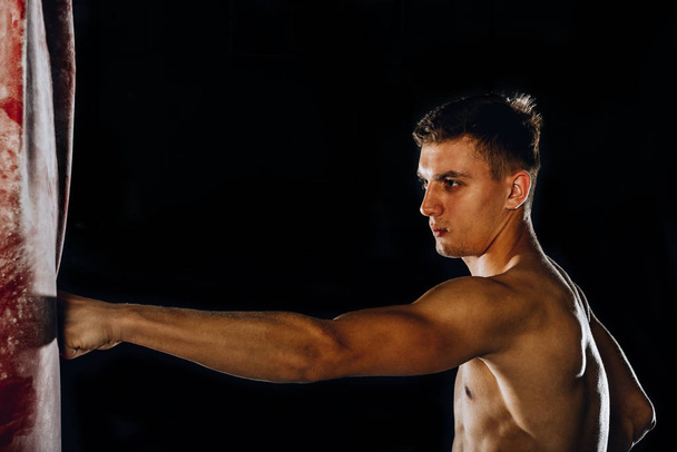 Lähikuva kuva valkoihoinen urheilija potkiminen nyrkkeilysäkki
 - Valokuva, kuva