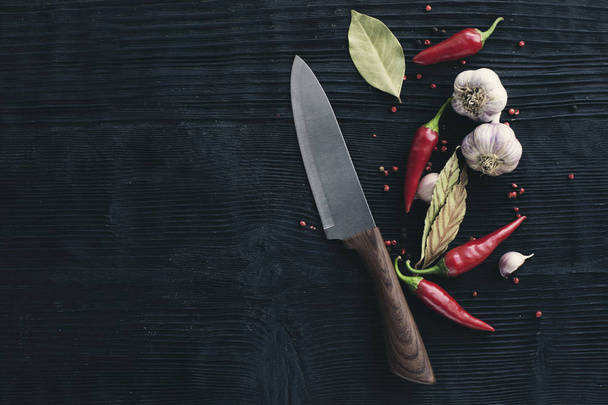 Chef  Knife garlic red chili pepper on black wooden background - Foto, afbeelding
