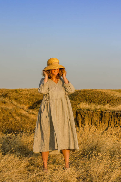 amazing girl in a hat at sunset in the steppe on the sea - Photo, Image