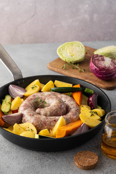Raw sausages with potatoes, zucchini, carrots and thyme in a grill pan. - Foto, Imagem