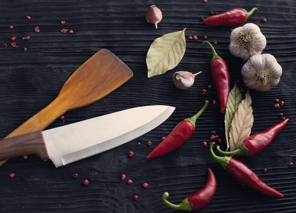Knife chef garlic red chili pepper on black wooden background - Фото, изображение