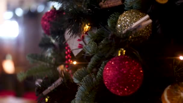 As bolas de Ano Novo e grinalda no fundo borrado, conceito de férias. Moldura. Composição de Natal de ramo de árvore de pinheiro, bolas de Natal douradas e vermelhas, bagas vermelhas
. - Filmagem, Vídeo