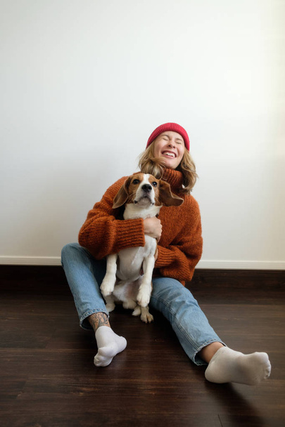 Girl in a sweater at home plays with a dog - Zdjęcie, obraz