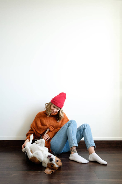 Girl in a sweater at home plays with a dog - Foto, imagen