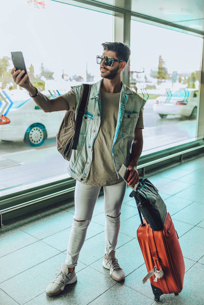 Gros plan portrait d'un jeune mec cool prenant selfie avec téléphone portable à l'aéroport
 - Photo, image