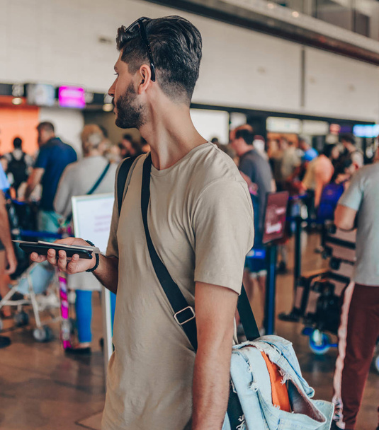 Turystyka, wakacje i koncepcja transportu - uśmiechnięty człowiek z torbą podróżną, biletem i paszportem na tle lotniska - Zdjęcie, obraz