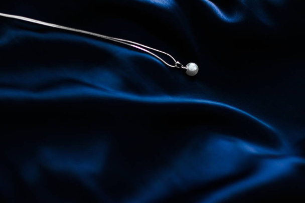 Luxury white gold pearl necklace on dark blue silk background, h - Photo, Image