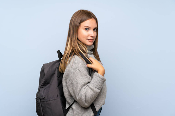 Menina adolescente com suéter sobre fundo azul isolado com mochila
 - Foto, Imagem