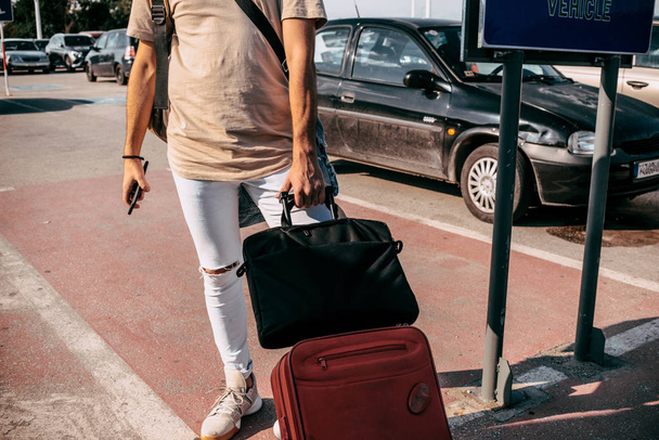 スマートカジュアルスタイルの服を着て旅行男輸送を待っている間に彼の荷物を離れて歩く - 写真・画像