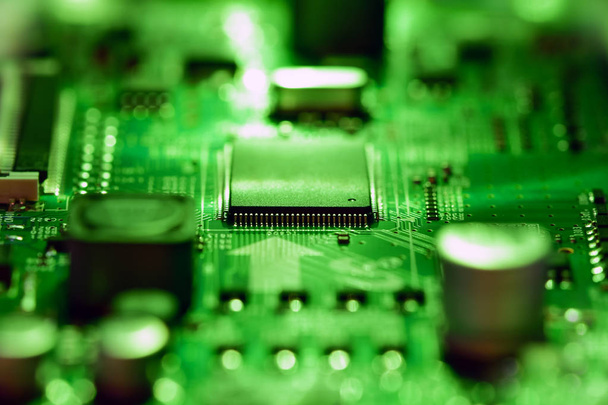 Επιλεκτική εστίαση, ενσωματωμένο ηλεκτρονικό κύκλωμα και μικροεπεξεργαστής σε φωτεινό πράσινο φως - Φωτογραφία, εικόνα