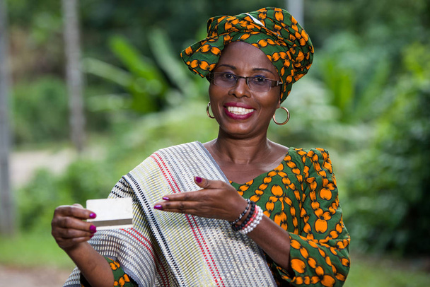πορτρέτο της αφρικανικής γυναίκας που παρουσιάζει μια πιστωτική κάρτα στο φόντο της φύσης - Φωτογραφία, εικόνα