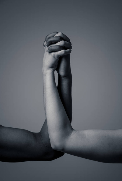 Multiracial couple holding hands together in love. White and black skin arms holding together. Conceptual image of world unity interracial love and understanding in tolerance and diversity. - Valokuva, kuva