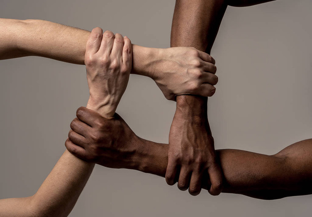 Wyścigi zjednoczeni przeciw dyskryminacji i rasizmowi. Czarne afroamerykańskie i kaukaski ręce trzymania razem w jedności świata i rasowej miłości i zrozumienia. Koncepcja tolerancji i współpracy. - Zdjęcie, obraz