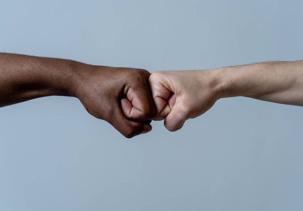 Black African American race male and white Caucasian woman hands giving a fist bump in agreement partnership and cooperation multiracial diversity and immigration concept. Stop racism campaign. - Фото, изображение