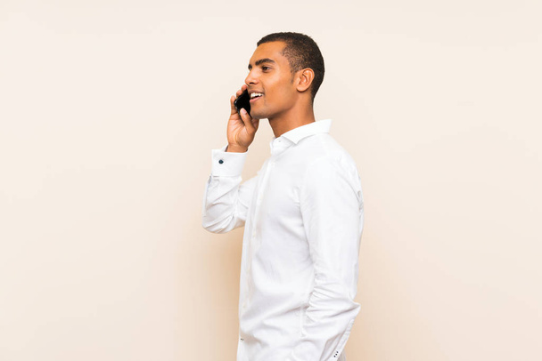 Cep telefonu ile bir konuşma tutmak izole arka plan üzerinde Genç yakışıklı esmer adam - Fotoğraf, Görsel