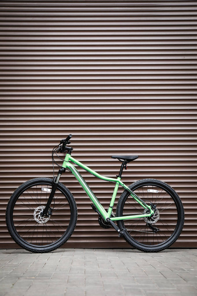 Nuova bicicletta a colori moderna vicino alla parete marrone all'aperto
 - Foto, immagini