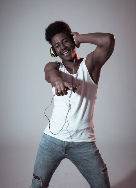 Strong african american young dancer man listening to music online dancing and singing with headphones. Artistic portrait with disco dance floor neon light in Internet Music and technology concept. - Photo, image