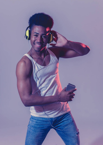 Forte afroamericano giovane ballerino che ascolta musica online ballare e cantare con le cuffie. Ritratto artistico con pista da ballo discoteca luce al neon in Internet Concetto musicale e tecnologico
. - Foto, immagini