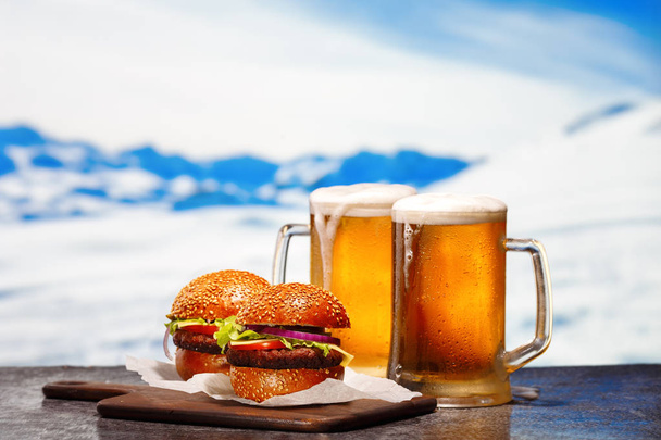 Two frosty mugs of light beer and two hamburgers - Foto, Bild