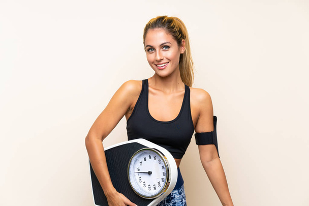 Young sport woman with weighing machine over isolated background - Foto, Imagem