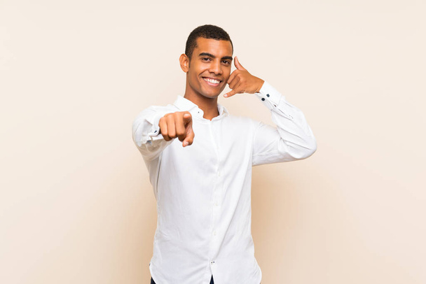Jeune homme brune beau sur fond isolé faisant geste de téléphone et pointant vers l'avant
 - Photo, image