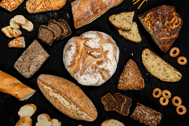 Sortiment verschiedener Brotsorten auf schwarzem Hintergrund. Ansicht von oben - Foto, Bild