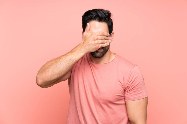 Красивый молодой человек на изолированном розовом фоне закрывая глаза руками
 - Фото, изображение