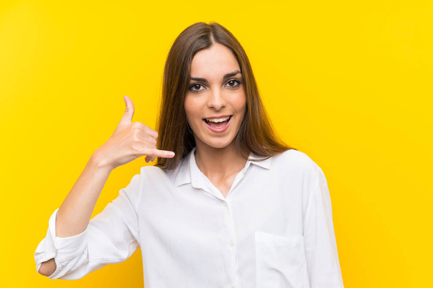 Young woman over isolated yellow background making phone gesture - Photo, Image