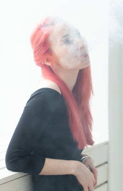 Vape, addiction and people concept - woman with red hair is smoking vape - Photo, Image