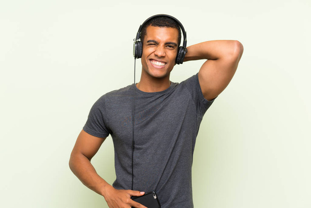 Nuori komea mies kuuntelee musiikkia mobiili yli eristetty vihreä seinä
 - Valokuva, kuva