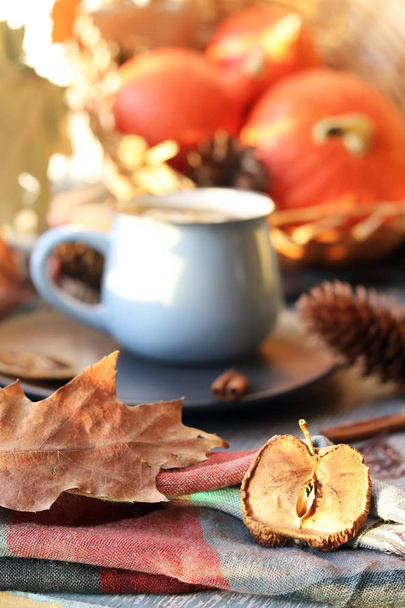 Xícara de café, abóboras, folhas, temperos, um lenço em uma superfície de madeira em um fundo de janela, conceito de conforto em casa, Ação de Graças, estação de outono
 - Foto, Imagem
