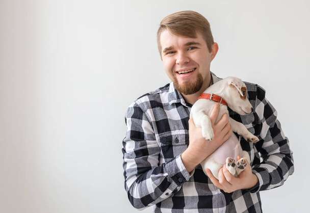 people, pets and animals concept - close up of young man holding jack russell terrier puppy on white background - Foto, immagini
