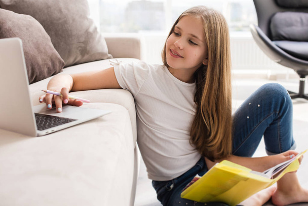 Evde dizüstü bilgisayar ve kitap ile Okul kız çalışma - Fotoğraf, Görsel