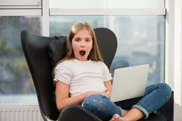 Surprised school girl with open mouth and laptop - Photo, Image