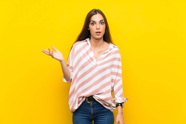 Young woman over isolated yellow background making doubts gesture - Fotoğraf, Görsel