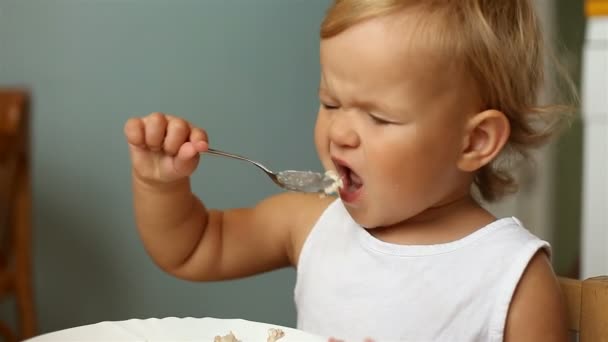 Little girl eats porridge - Кадры, видео
