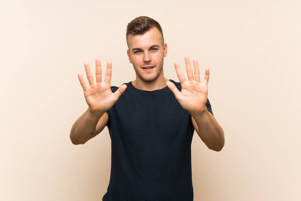 Young handsome blonde man over isolated background counting ten with fingers - Photo, Image
