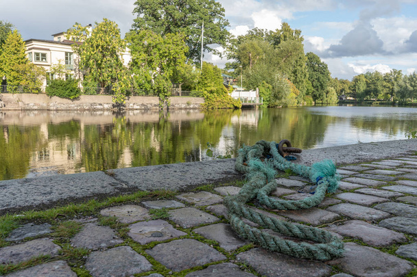 Old, green rope lies on rocky street by river. Orebro city center. Travel photo, background image or illustration. - Photo, Image
