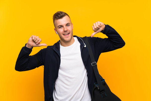 Young blonde sport man over isolated yellow background proud and self-satisfied - Foto, Imagem