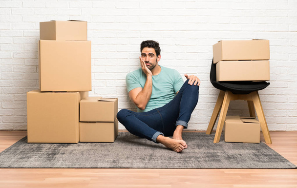 Komea nuori mies muuttamassa uuteen kotiin laatikoiden joukossa onneton ja turhautunut
 - Valokuva, kuva