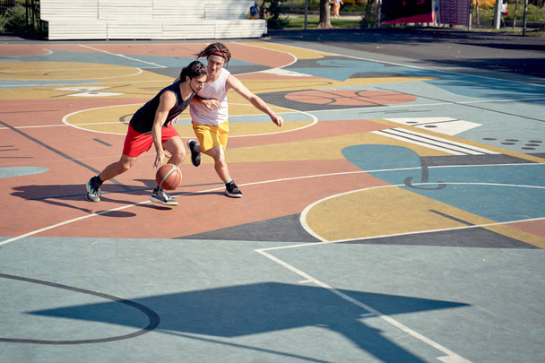 Photo of sportsmen playing basketball on playground . - Foto, afbeelding