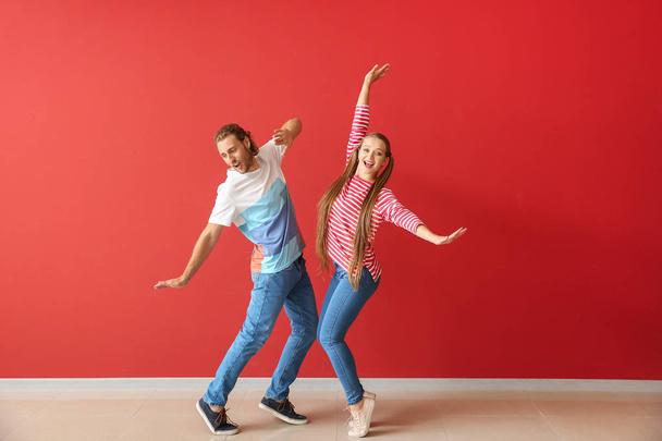 色の壁に対して踊るクールな若いカップル - 写真・画像