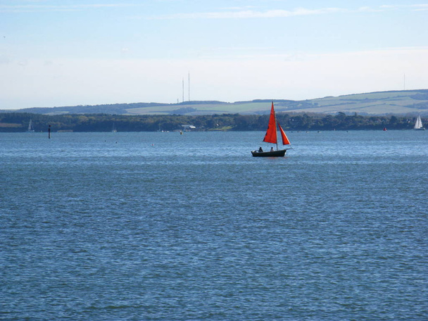Прозрачное, прекрасное утро на морском побережье. Красный парусник. Фотография сделана 14 октября 2012 года. Лаймингтон. Англия
. - Фото, изображение