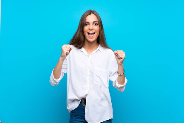 Young woman over isolated blue background celebrating a victory in winner position - Photo, Image