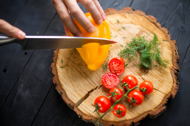 Chef cook cuts yellow bell pepper on a wooden board, closeup. - Foto, immagini