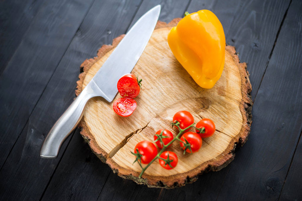 Knife and fresh cherry tomatoes on a wooden board, closeup. - Photo, image