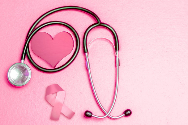 Pink heart and awareness ribbon with a stethoscope on a colored  - Фото, изображение