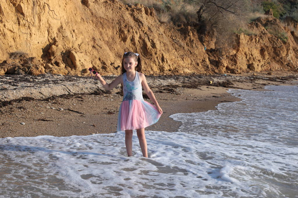 Трохи пустотливої і веселої дівчини вісім років з довгим коричневим волоссям стрибає на хвилях і сміється з задоволенням від літніх канікул
 - Фото, зображення