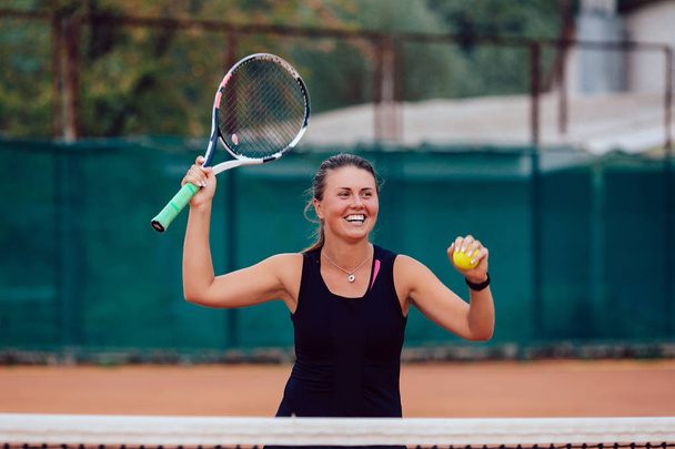 Tennis player. Cheerful beautiful girl playing tennis, prepares to serve a tennis ball. Dressed in black t-shirt. - Fotó, kép